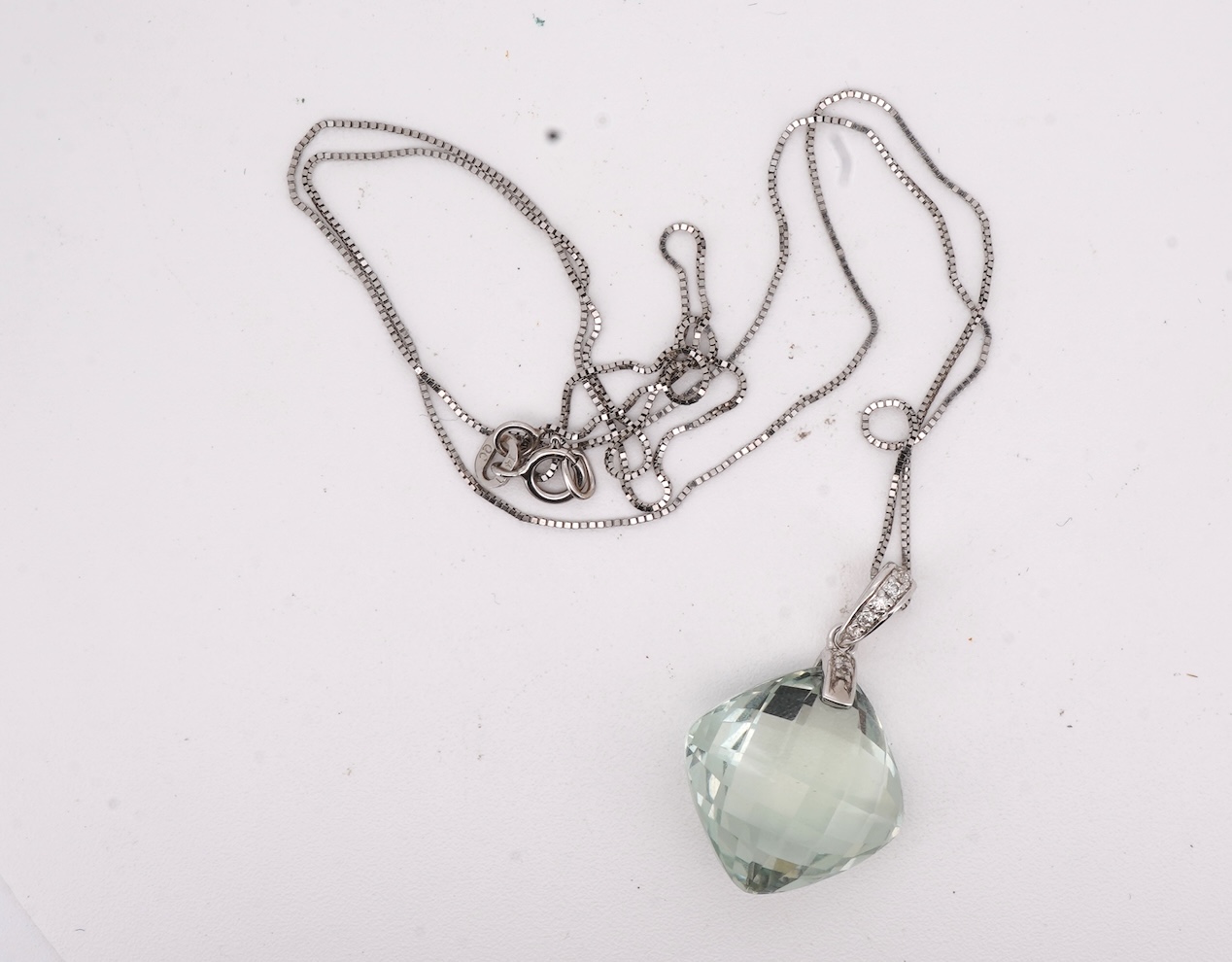 A prasiolite and diamond pendant, the diamond-set bail suspending a cushion-shaped chequerboard-cut prasiolite, to a fine link chain, mounted in 14ct gold, pendant length 2.5cm, chain length 46cm, British hallmarks, gros